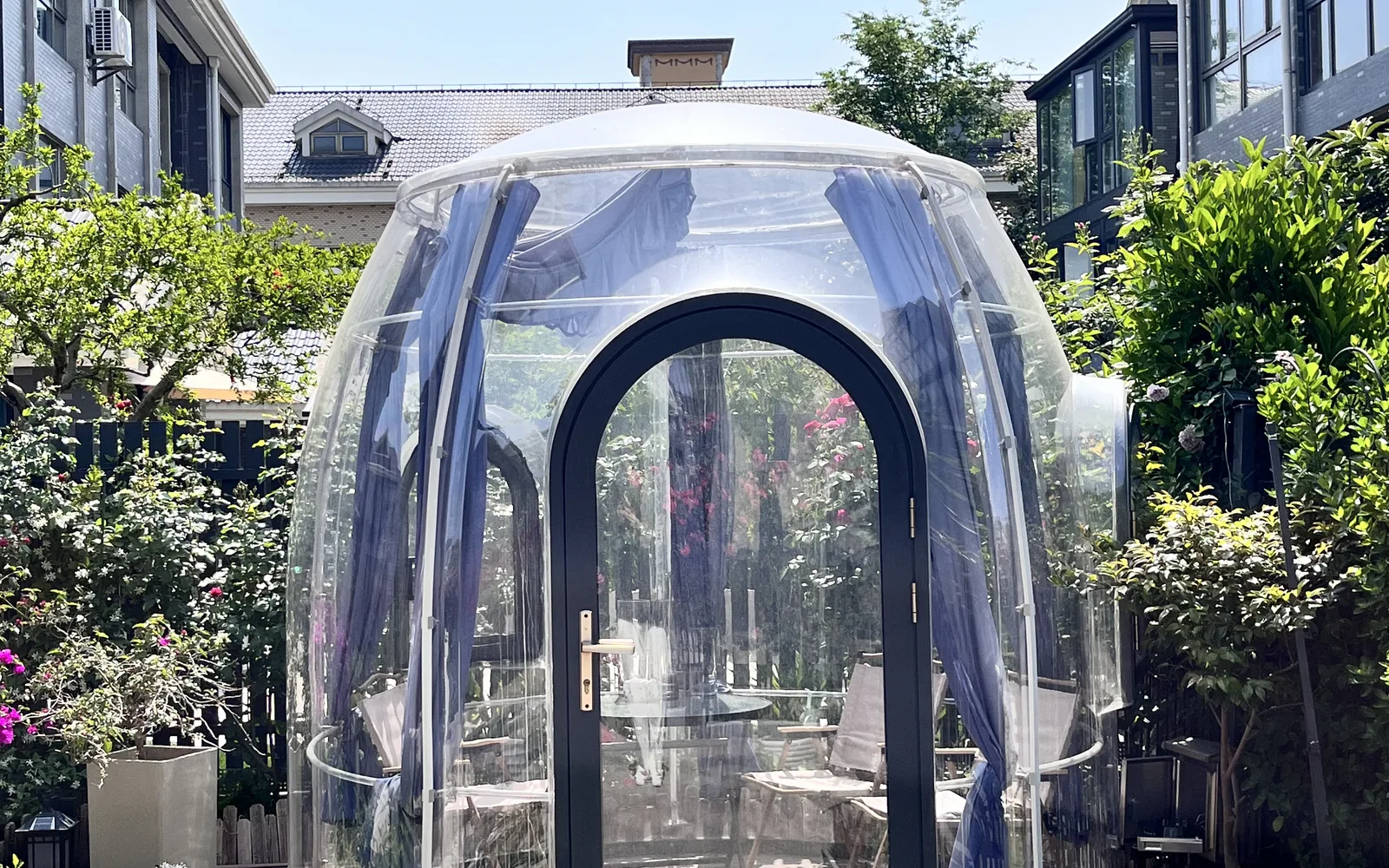Compact transparent Domevora dome installed beside a residential garden