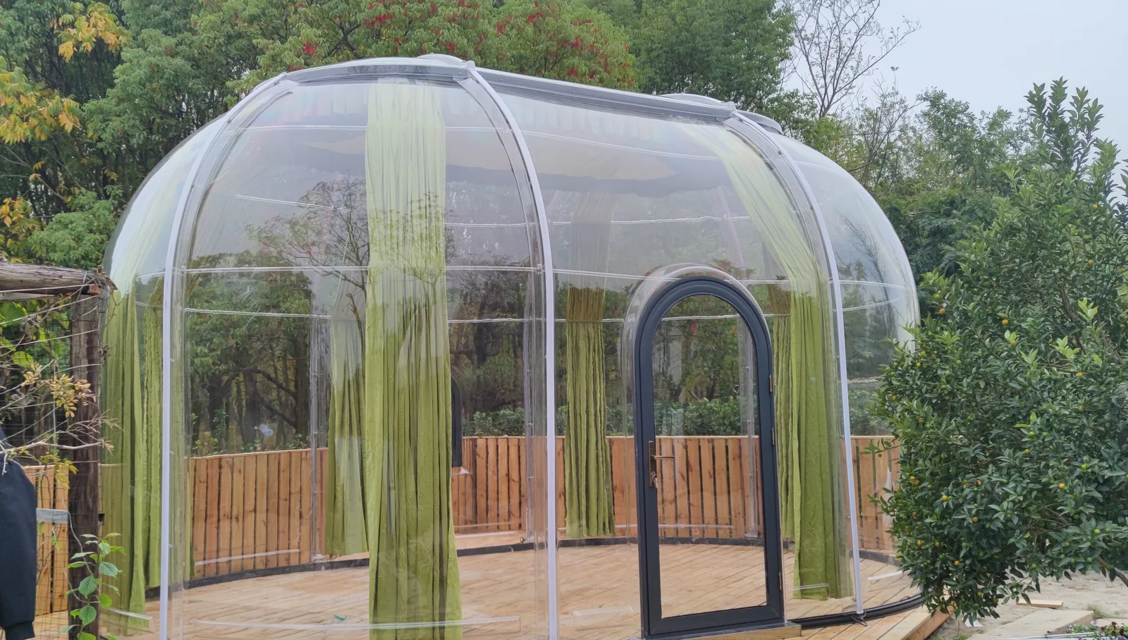 Transparent Domevora dome on a timber deck in a planted garden