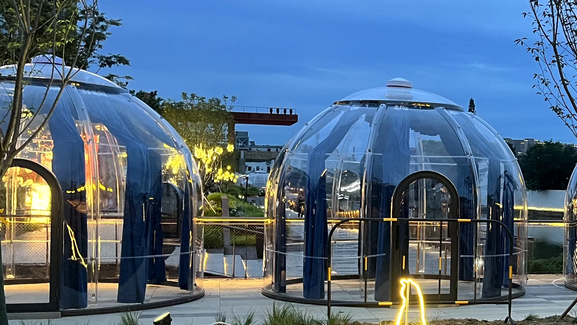 Two transparent Domevora domes lit from within at blue hour
