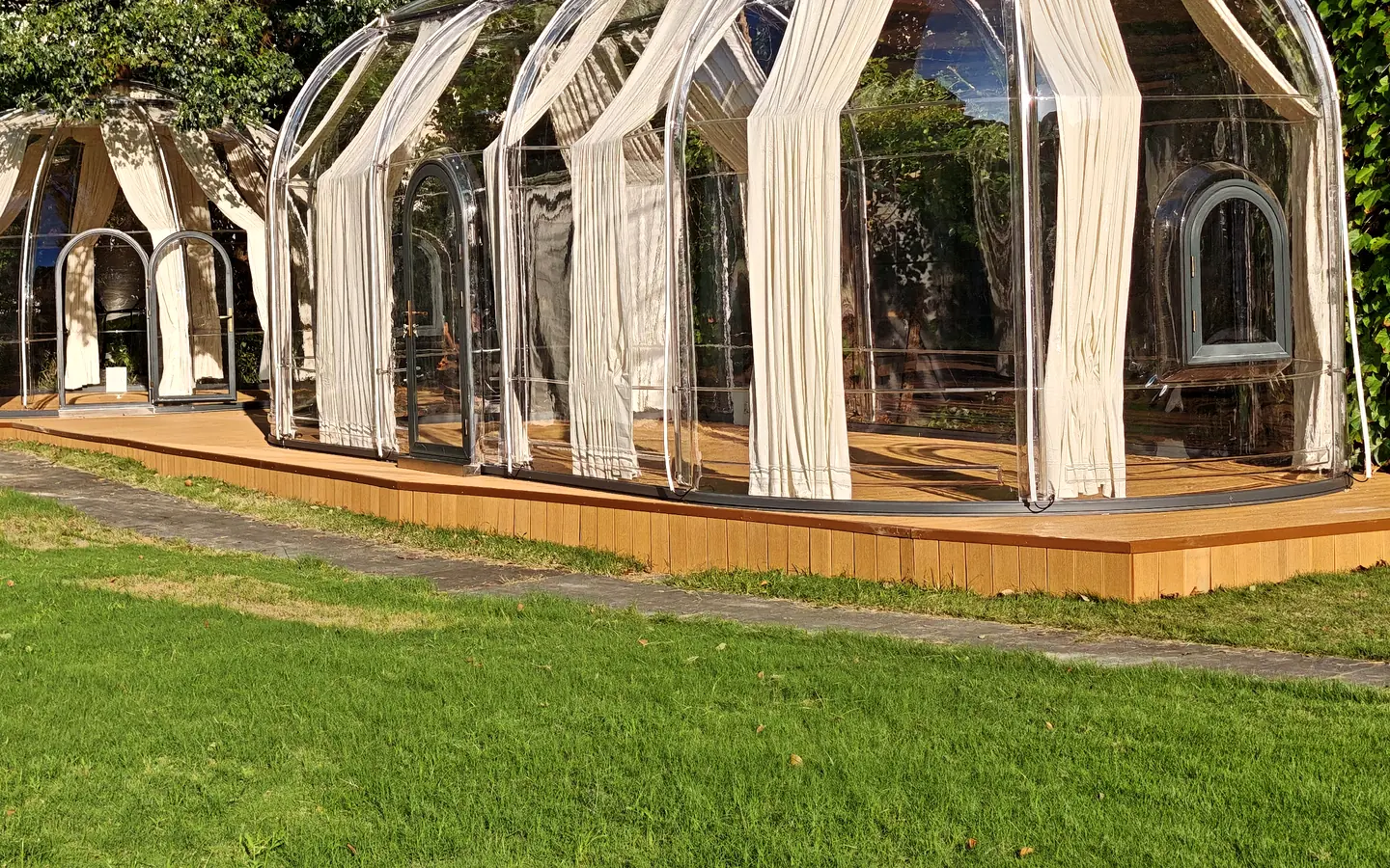 Extended oval Domevora dome with curtains on a timber deck