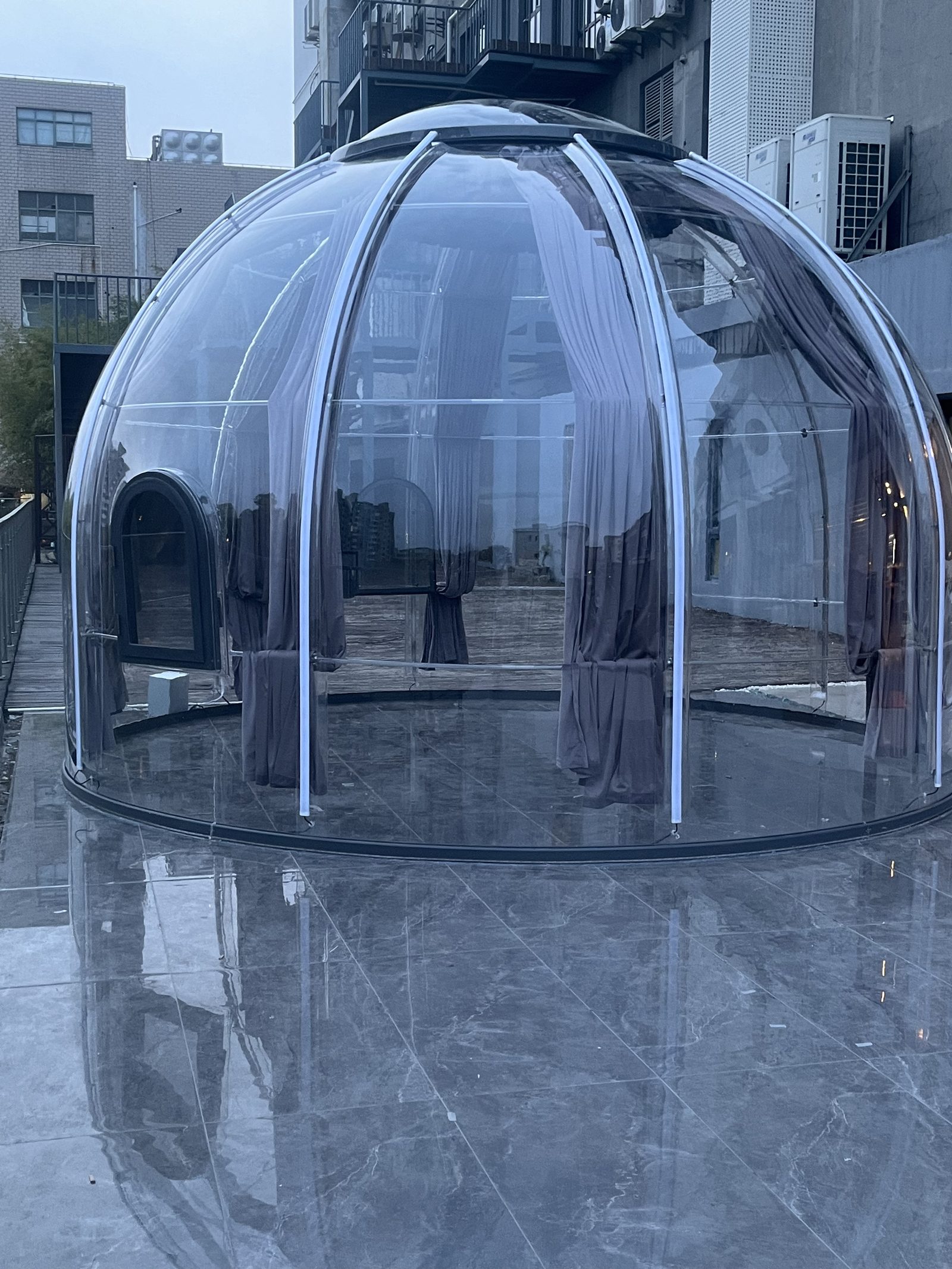 Polycarbonate dome on a city terrace at dusk with grey shading curtain