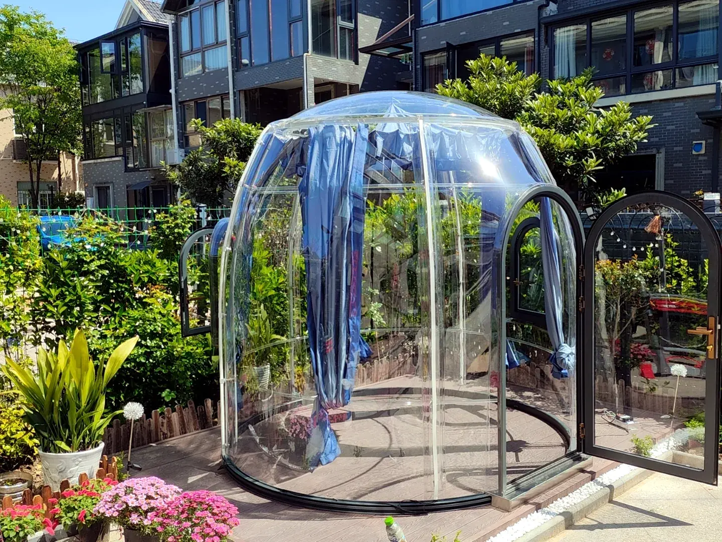 Round 2.5 m clear polycarbonate dome in a residential front garden with the door open
