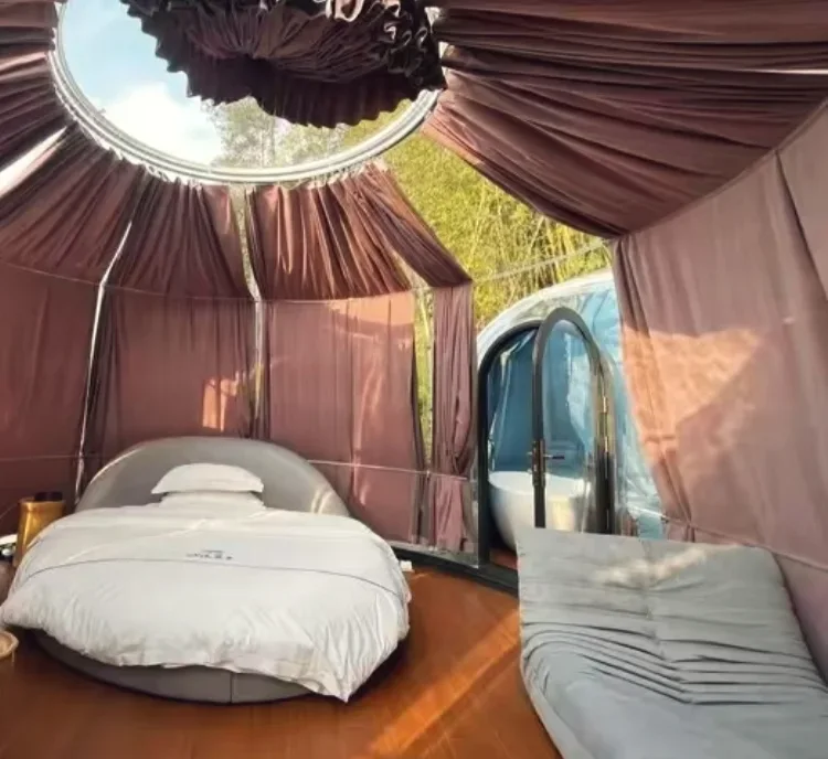 Guest room inside a Domevora dome, client installation: round bed, raised roof opening and a linked bathroom dome with a freestanding tub