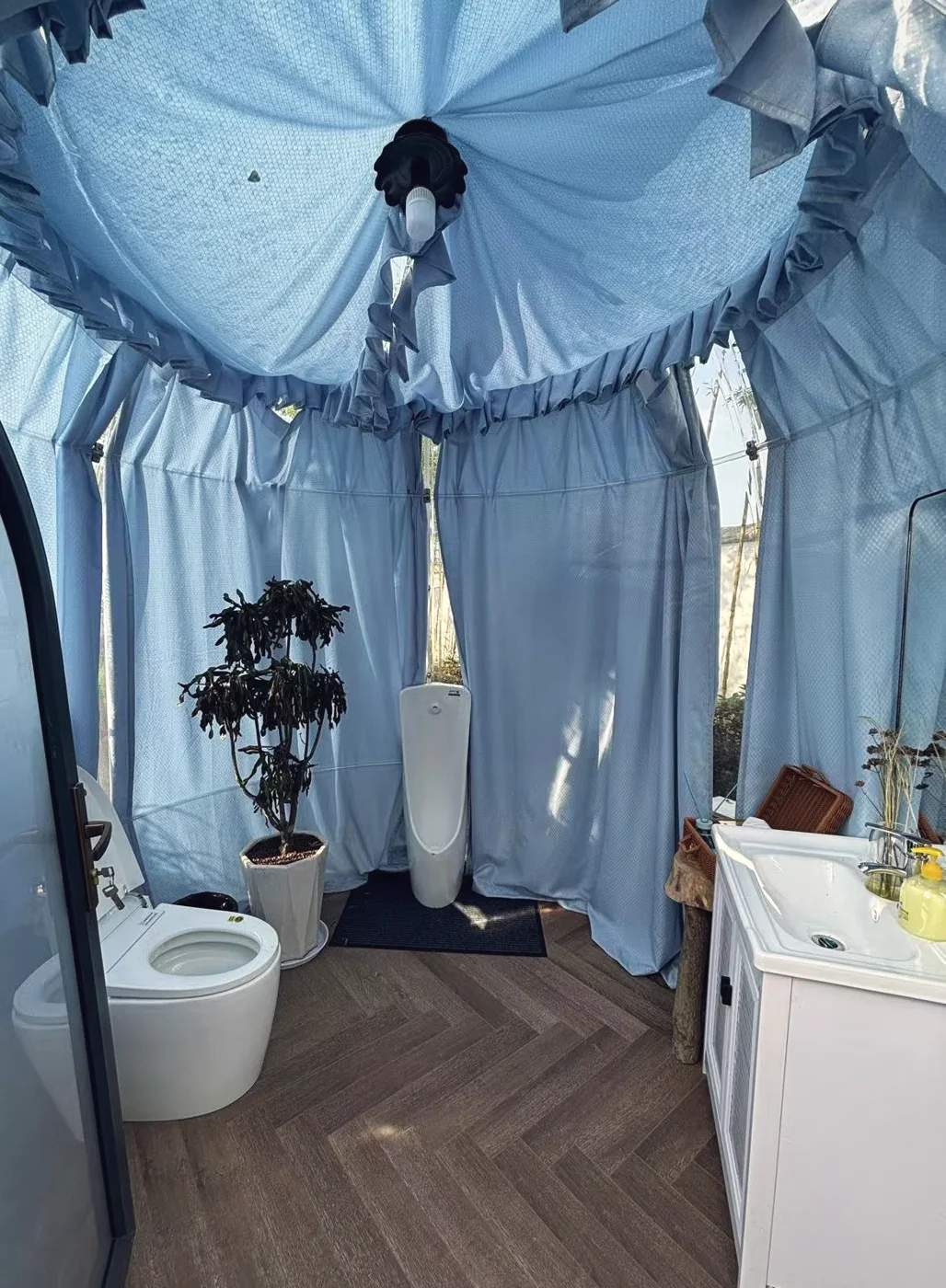 Round 2.5 m Domevora dome fitted out as a guest bathroom: toilet, urinal and vanity unit under ceiling drapes