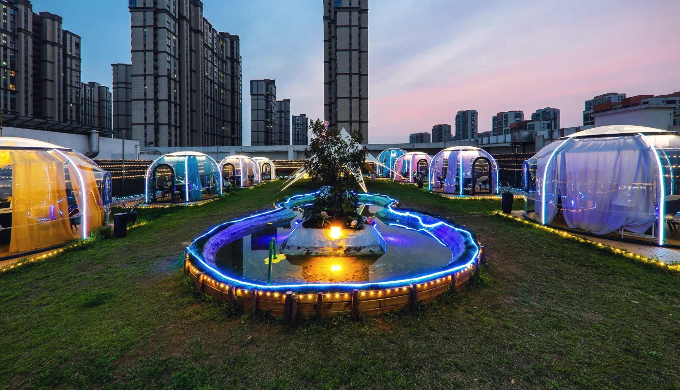 Round 3.5 m High Domevora dome, client installation: a rooftop garden with a cluster of dining domes around a lit pond