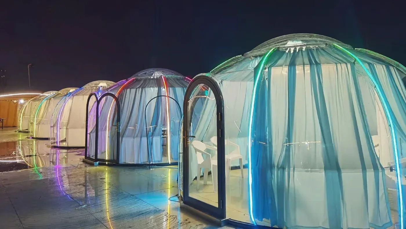 Round 4.0 m Low Domevora dome, client installation: a row of dining domes with coloured LED lighting at night